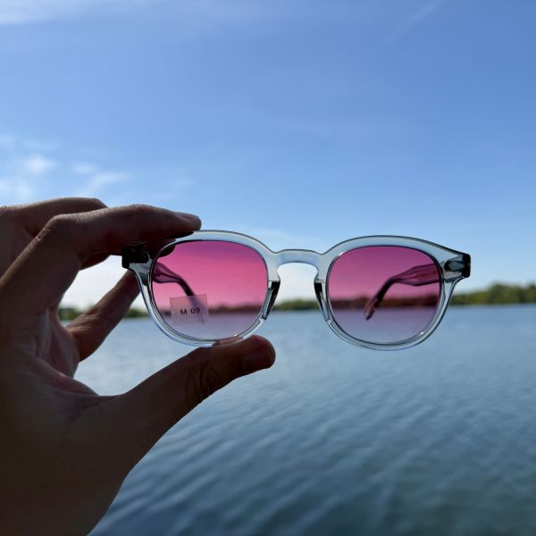 Lunettes de soleil aux verres roses portées face au coucher du soleil chez Optique Audition Suin Valenciennes