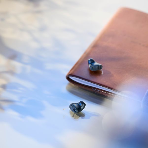 Appareil auditif intra-auriculaire discret posé sur un carnet chez Optique Audition Suin Valenciennes