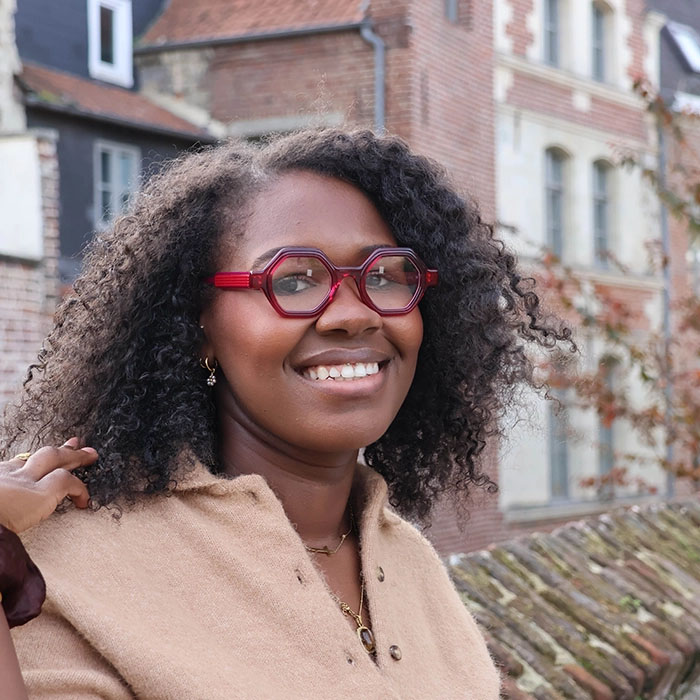 Lunettes créateur colorées disponibles en ligne chez Optique Audition Suin Femme souriante portant des lunettes créateur rouges sur l’e-boutique Optique Audition Suin Valenciennes