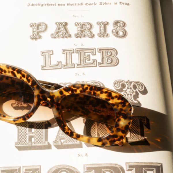 L’élégance des matières et l’esprit mode intemporel Détail de lunettes écaille devant un univers mode et vintage chez Optique Audition Suin Valenciennes
