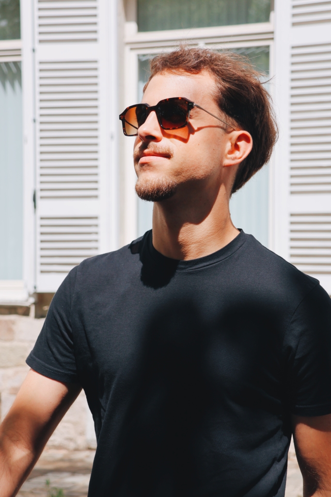 Homme portant des lunettes de soleil élégantes, photographié en extérieur, style urbain et intemporel – Optique Audition Suin Valenciennes